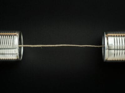 Two tin cans joined by a taut string on a black background, representing Bookably text alerts for booking updates